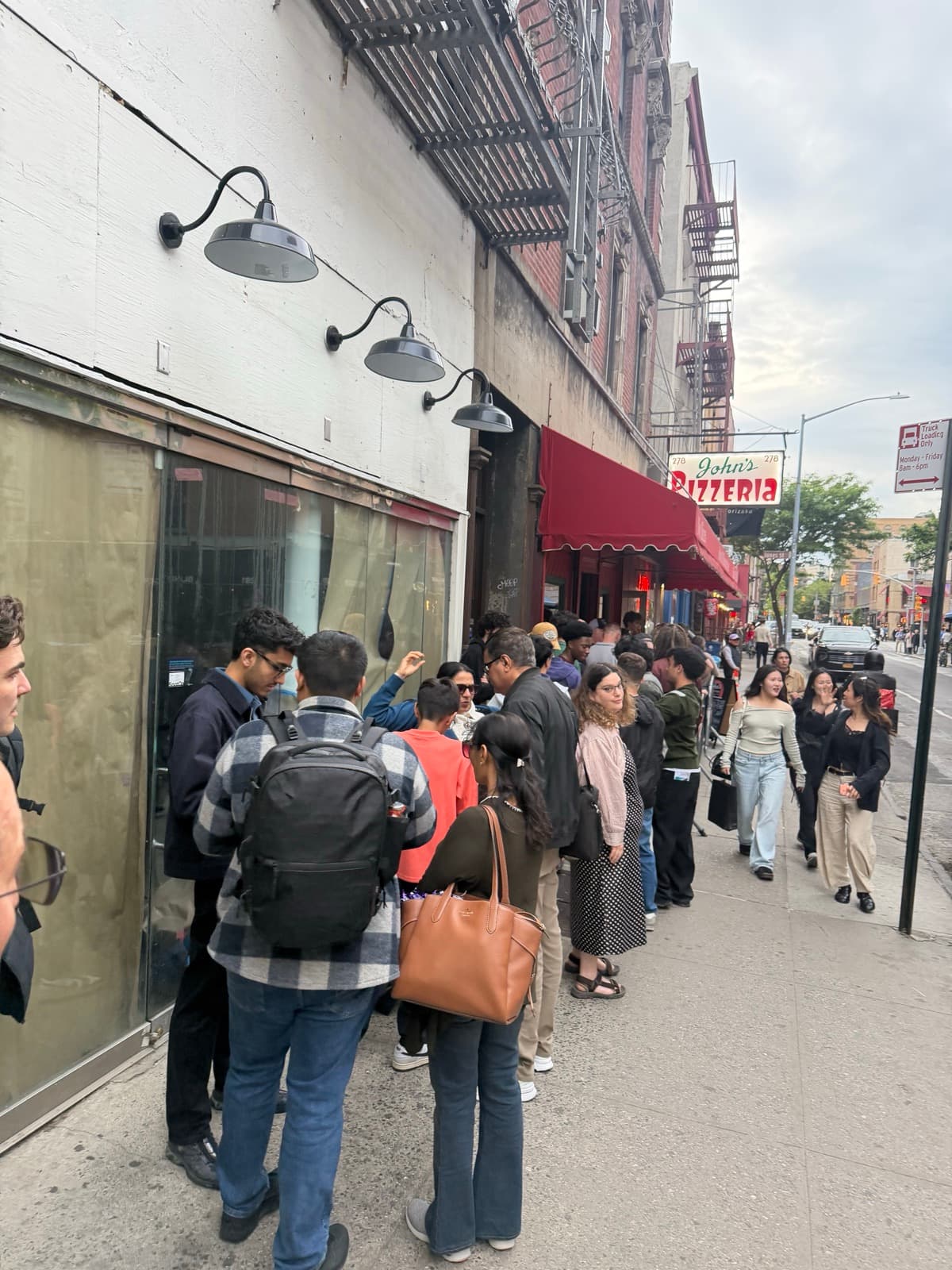 A line of people waiting outside John's of Bleecker Street pizzeria in New York